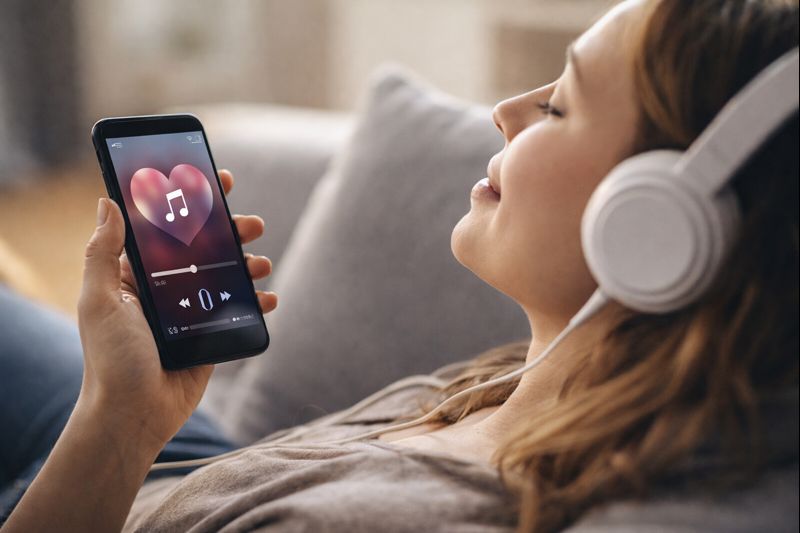 شخص يستمع بسماعات ويكرر مقطعًا موسيقيًا مع تعبير تركيز يوحي بتعلق ذهني ولحظة تكرار لا إرادية.